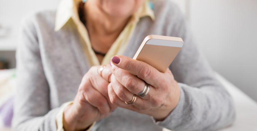 A close up of an older woman holding a cell phone in her hands.