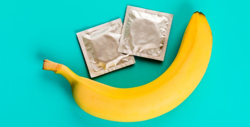 Two condoms and a banana on a bright blue background.