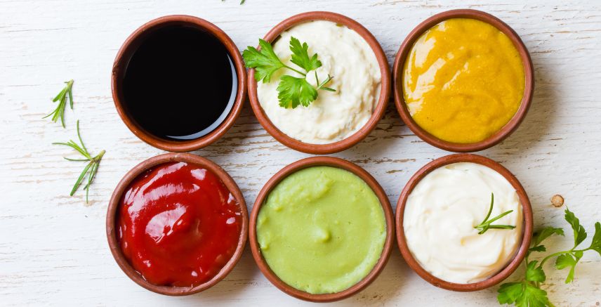 Six small dishes of various condiments and sauces.