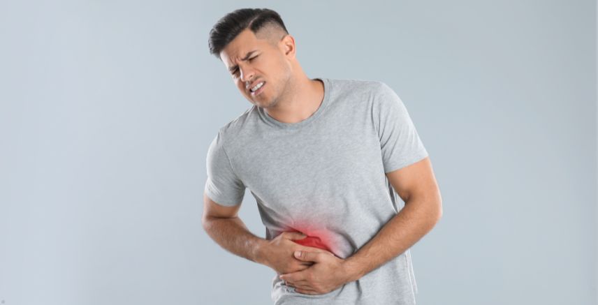 A man holding his stomach, which has red coloring over it to illustrate abdominal pain.
