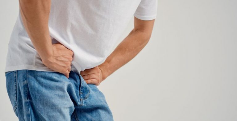 A man bending over with his hands on his groin.