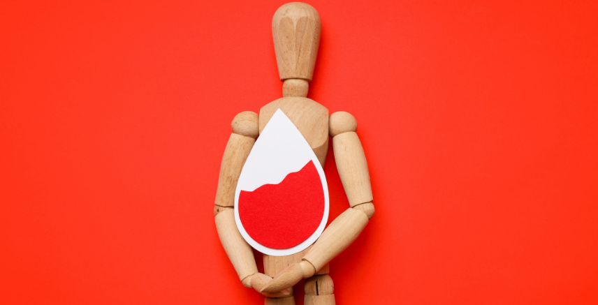 A wooden model of a human holding a white rain drop with red filling to indicate blood.